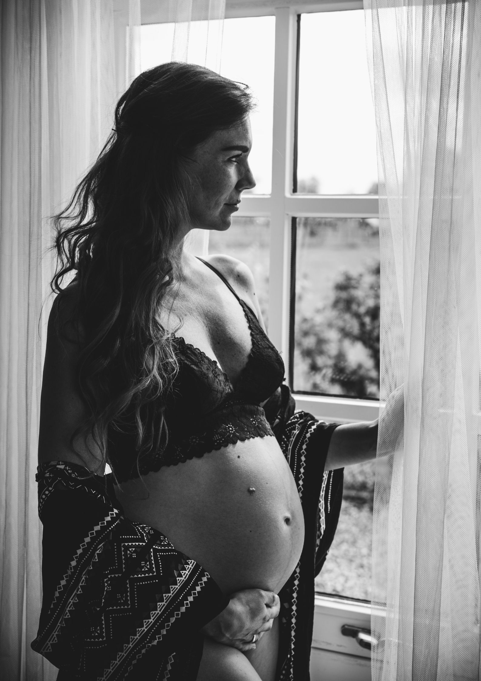 Close-up van zwangere buik tijdens zwangerschapsfotografie bij raam, Hoorn